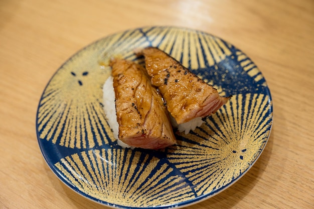 Une assiette avec une assiette bleue et jaune qui dit " sushi " dessus.