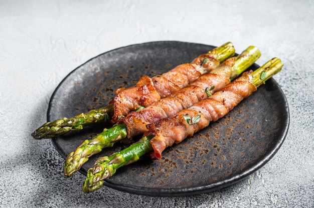 Assiette avec bacon de porc enveloppé d'asperges sur une table grise Fond blanc Vue de dessus