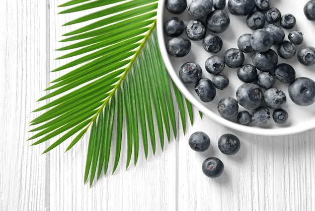 Assiette avec baies d'açai fraîches et feuille de palmier sur table en bois