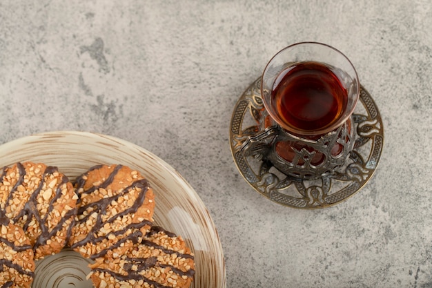 Assiette de biscuits aux éclats glacés et verre de thé sur pierre.