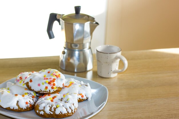Photo une assiette de biscuits glacés avec des paillettes dessus à côté d'une cafetière.