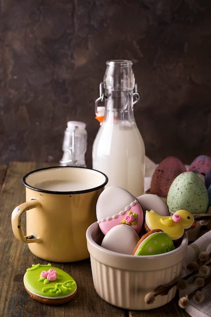 Assiette avec des biscuits de Pâques colorés et un verre de lait, style rustique