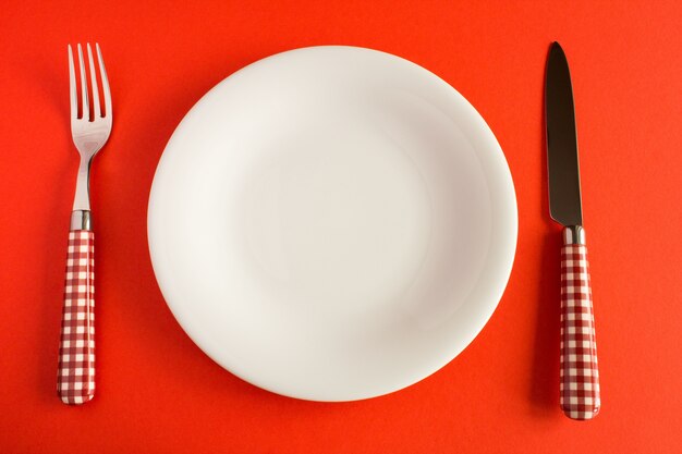 Assiette blanche avec couteau et fourchette sur la table