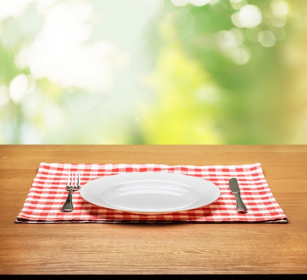 Assiette blanche et couverts sur fond de table