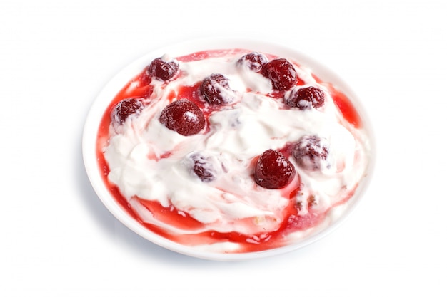 Assiette blanche avec du yogourt grec et de la confiture de fraises isolée sur blanc.