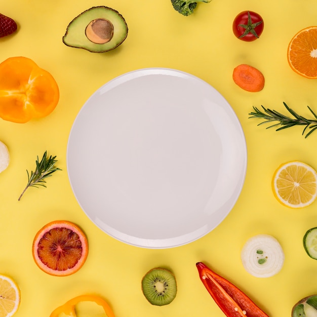 Assiette blanche entourée de légumes et de fruits