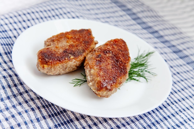 Assiette blanche avec escalopes de boeuf posées sur un torchon traditionnel à carreaux