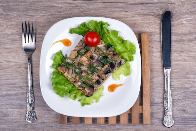 Une assiette blanche avec gratin de champignons et légumes verts