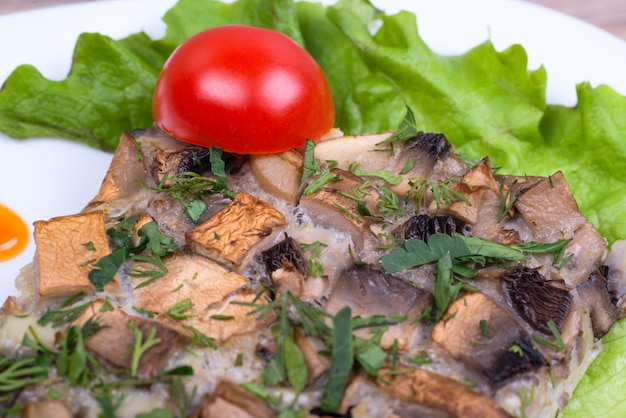 Une assiette blanche avec gratin de champignons et légumes verts