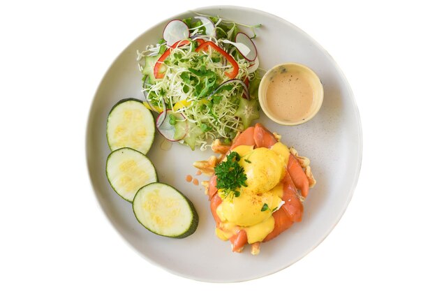 assiette blanche avec des œufs, des gaufres avec du saumon fumé sur un fond blanc