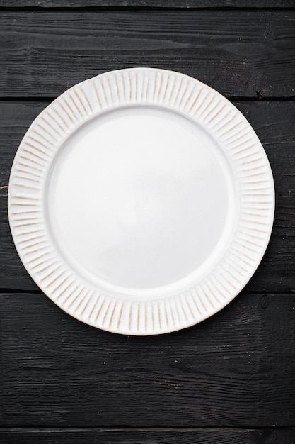 Photo assiette blanche en porcelaine vide avec espace de copie pour le texte ou la nourriture avec espace de copie pour le texte ou la nourriture, vue de dessus à plat, sur fond de table en bois noir