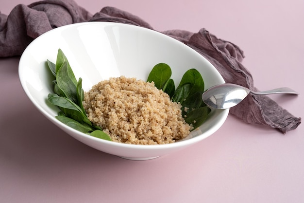 Assiette blanche avec quinoa cuit et feuilles d'épinards