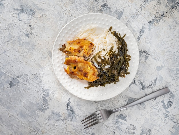 Assiette blanche avec riz et poisson de mer, salade d'algues