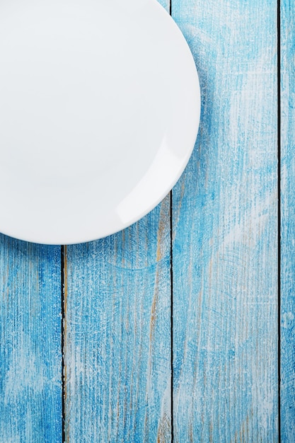 Photo une assiette blanche ronde vide sur une table en bois bleue. vue de dessus