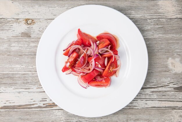 Assiette blanche et salade de tomates avec poulet grillé feuilles vertes et légumes vue d'en haut