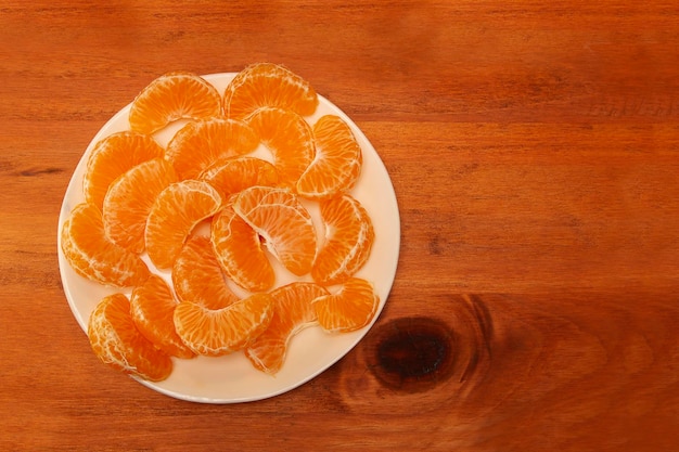 Assiette blanche sur une table en bois avec des segments de mandarine