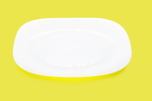 Assiette blanche vide sur fond jaune isolé espace pour fond de texte