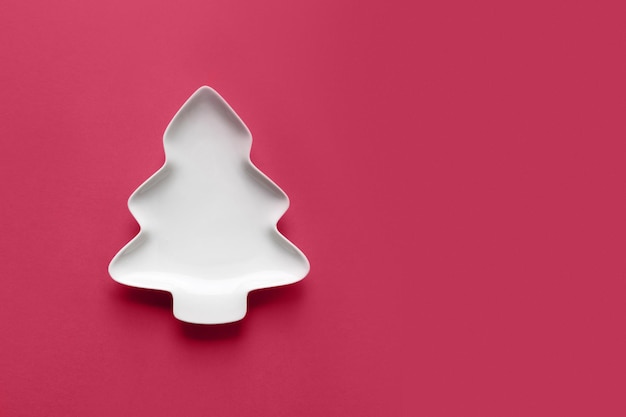 Assiette blanche vide en forme d'arbre de Noël sur fond magenta viva