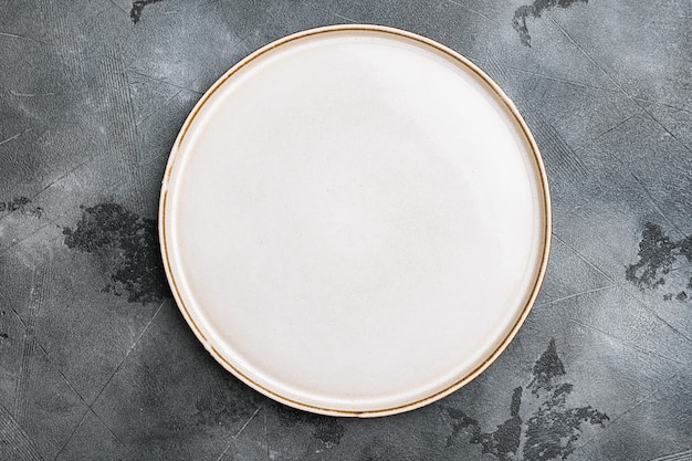 Assiette blanche vide en porcelaine sertie d'espace de copie pour le texte ou la nourriture avec espace de copie pour le texte ou la nourriture, vue de dessus à plat, sur fond de table en pierre grise