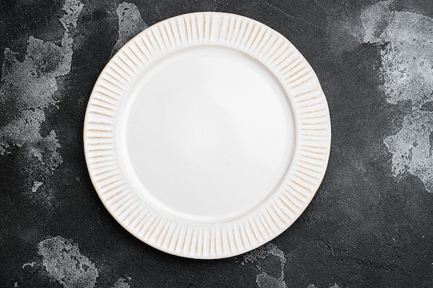 Assiette blanche vide en porcelaine sertie d'espace de copie pour le texte ou la nourriture avec espace de copie pour le texte ou la nourriture, vue de dessus à plat, sur fond de table en pierre noire noire