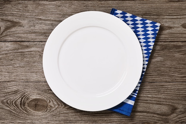 Assiette blanche vide avec serviette bavaroise sur une table en bois alimentaire