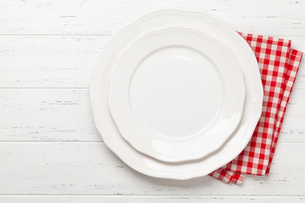 Un assiette blanche vide et une serviette sur une table en bois.