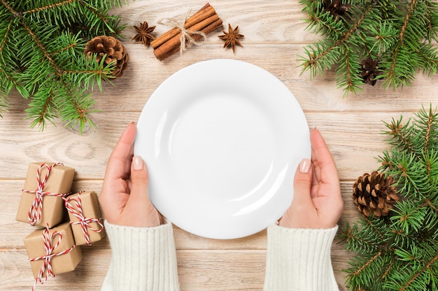 Assiette blanche vide sur une surface en bois avec décoration de Noël