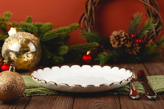 Assiette blanche vide à la table de Noël servie parmi les décorations.