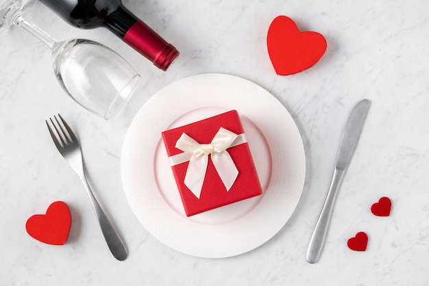 Assiette blanche vide avec vaisselle, ruban, cadeau et roses pour la Saint-Valentin