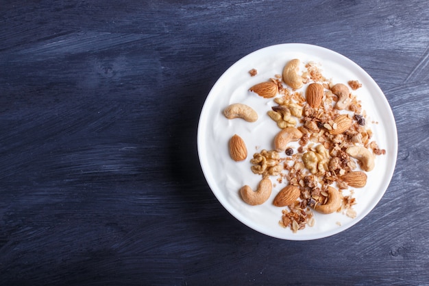 Assiette blanche avec yaourt grec, granola, amande, noix de cajou, noix de Grenoble