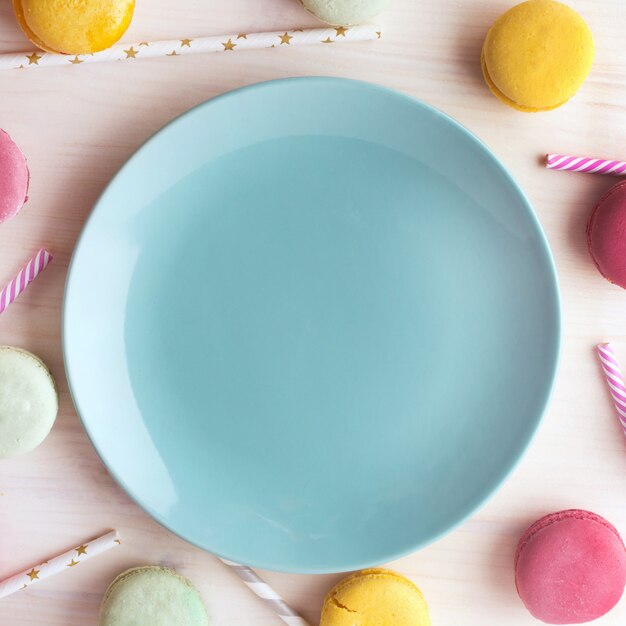 Assiette bleue brillante vide, avec de délicieux macarons