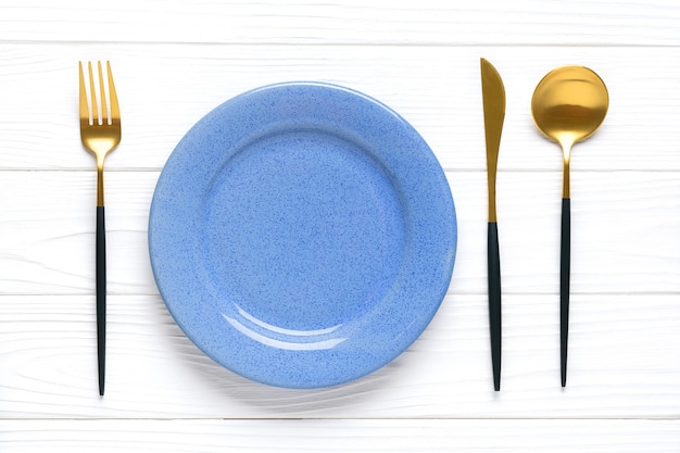 Assiette bleue avec couverts dorés