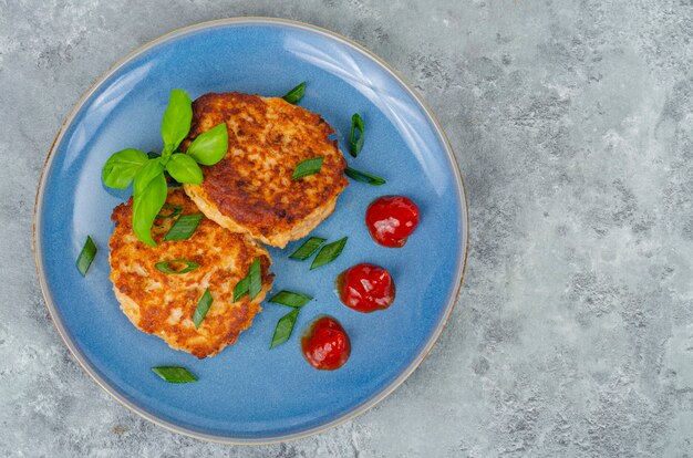 Assiette bleue avec deux escalopes de viande hachée. Studio photo.