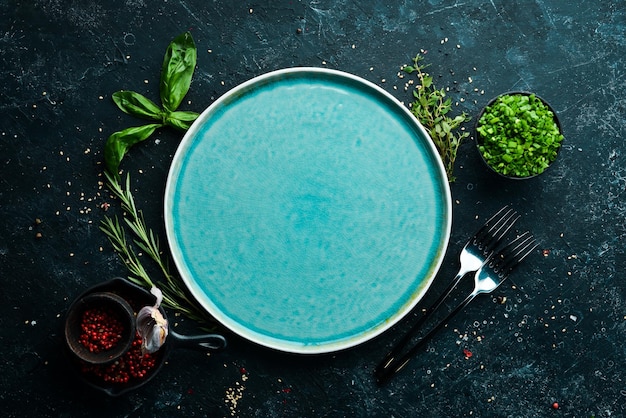 Assiette bleue avec légumes et épices sur fond de pierre noire Vue de dessus Style rustique