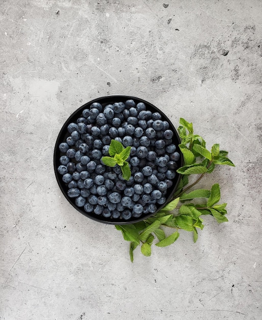 Assiette avec bleuets frais et brin de menthe sur fond clair