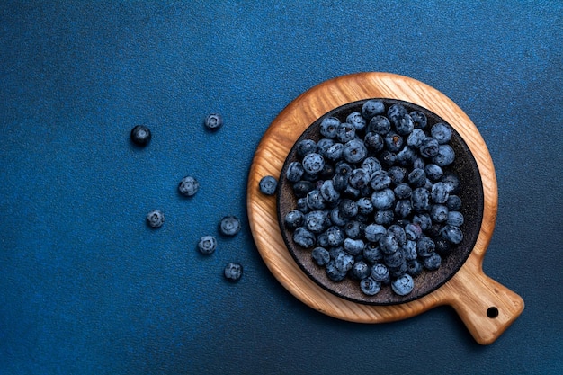 Assiette avec des bleuets frais sur fond bleu. Conseil avec des baies fraîches. Vue d'en-haut. Concentrez-vous sur l'assiette