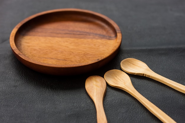 Assiette en bois brun et cuillère en bois couleur noire dans le restaurant de la cuisine fait maison