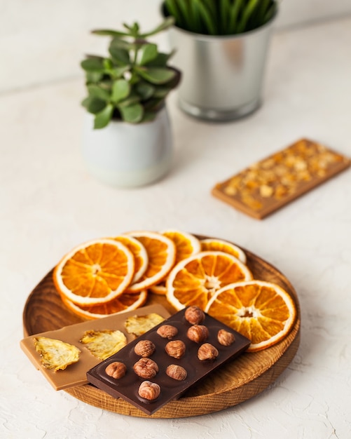 Assiette en bois de chocolat au lait au chocolat végétalien avec du chocolat et des fruits secs