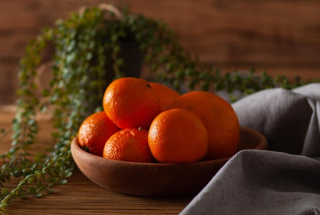 Une assiette en bois avec des mandarines sur la table