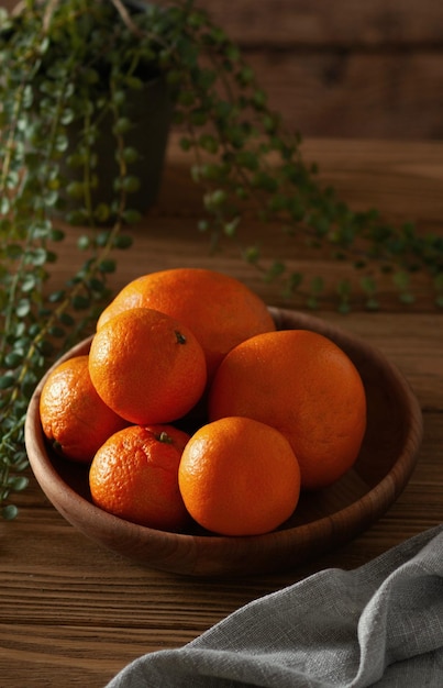 Une assiette en bois avec des mandarines sur la table