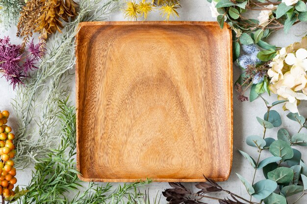 Assiette en bois et ornements botaniques sur une table en marbre