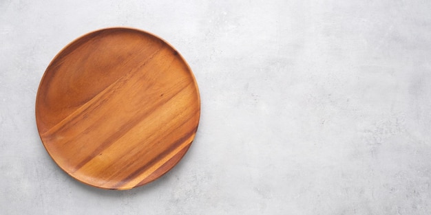 Assiette en bois ronde vide sur fond de table en ciment gris