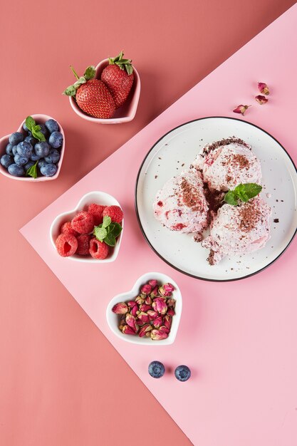 Assiette avec boules de glace aux baies et petites assiettes en forme de coeurs avec baies fraîches fraises framboises myrtilles, vue de dessus