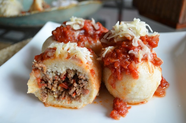 Une assiette de boulettes de viande farcies de spaghettis avec une tranche de sauce tomate.