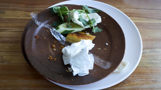 Une assiette brune remplie de restes de nourriture tissu pipette emballage plastique est arrivé après avoir fini de manger un moment nettoyage avec du tissu et mettre tous les ustensiles dans le bol