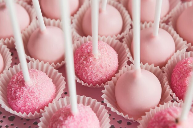 Assiette de cake pops avec glaçage rose, gros plan. Bar à bonbons et concept de restauration pour anniversaire, mariage et autres célébrations de vacances