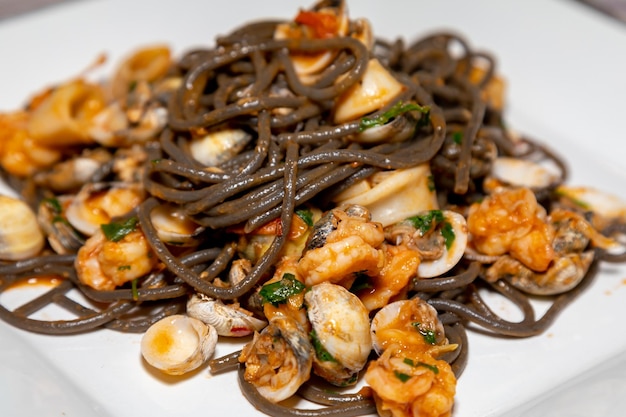 Une assiette de calamars noirs avec une sauce et de la sauce.