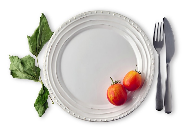 Assiette en céramique blanche décorée de feuilles de cassis séchées et de tomates