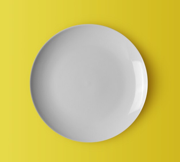 Assiette en céramique blanche sur fond jaune