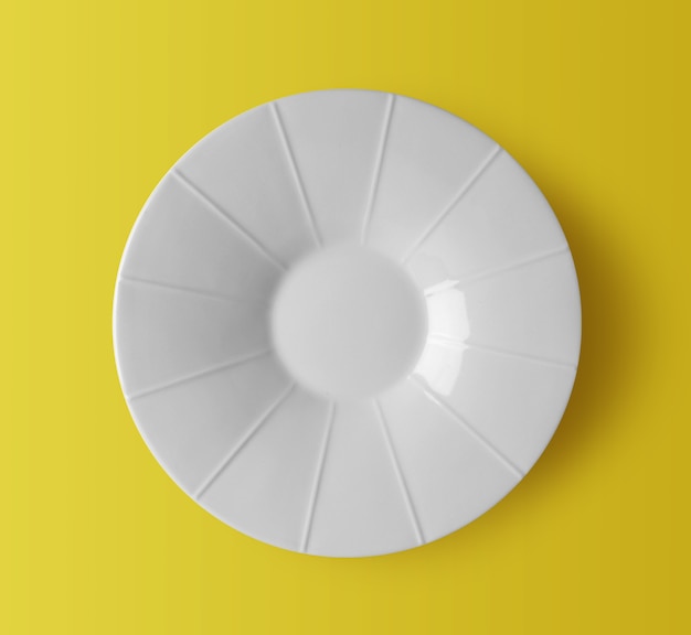 Assiette en céramique blanche sur fond jaune